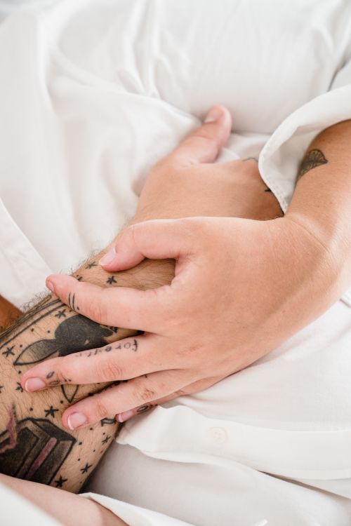 Free Close-up of a couple's hands gently holding each other in an intimate setting, symbolizing comfort and connection. Stock Photo