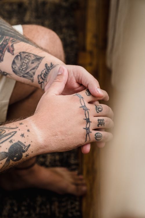 Free Close-up of a tattooed man sitting with hands clasped, creating a thoughtful mood. Stock Photo