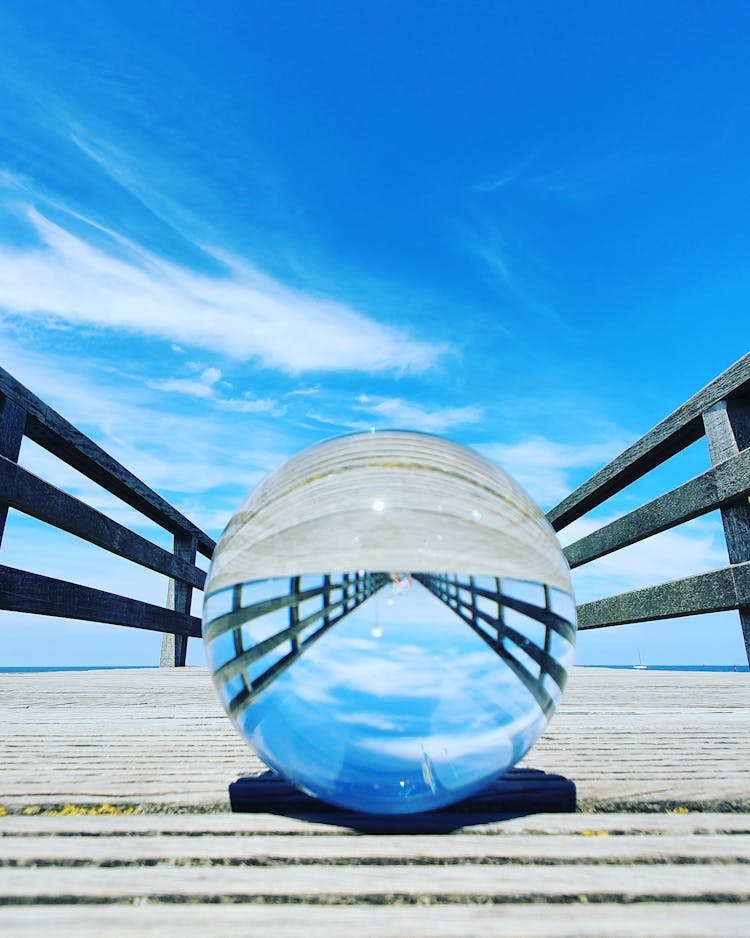 A Clear Glass Ball On Wooden Bridge Under The Blue Sky