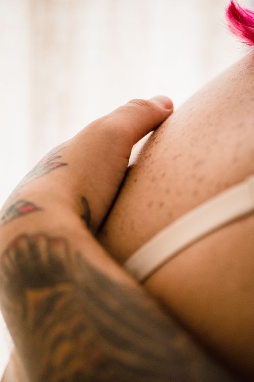 Free Intimate close-up of a tattooed arm embracing a bare shoulder, conveying love and connection. Stock Photo