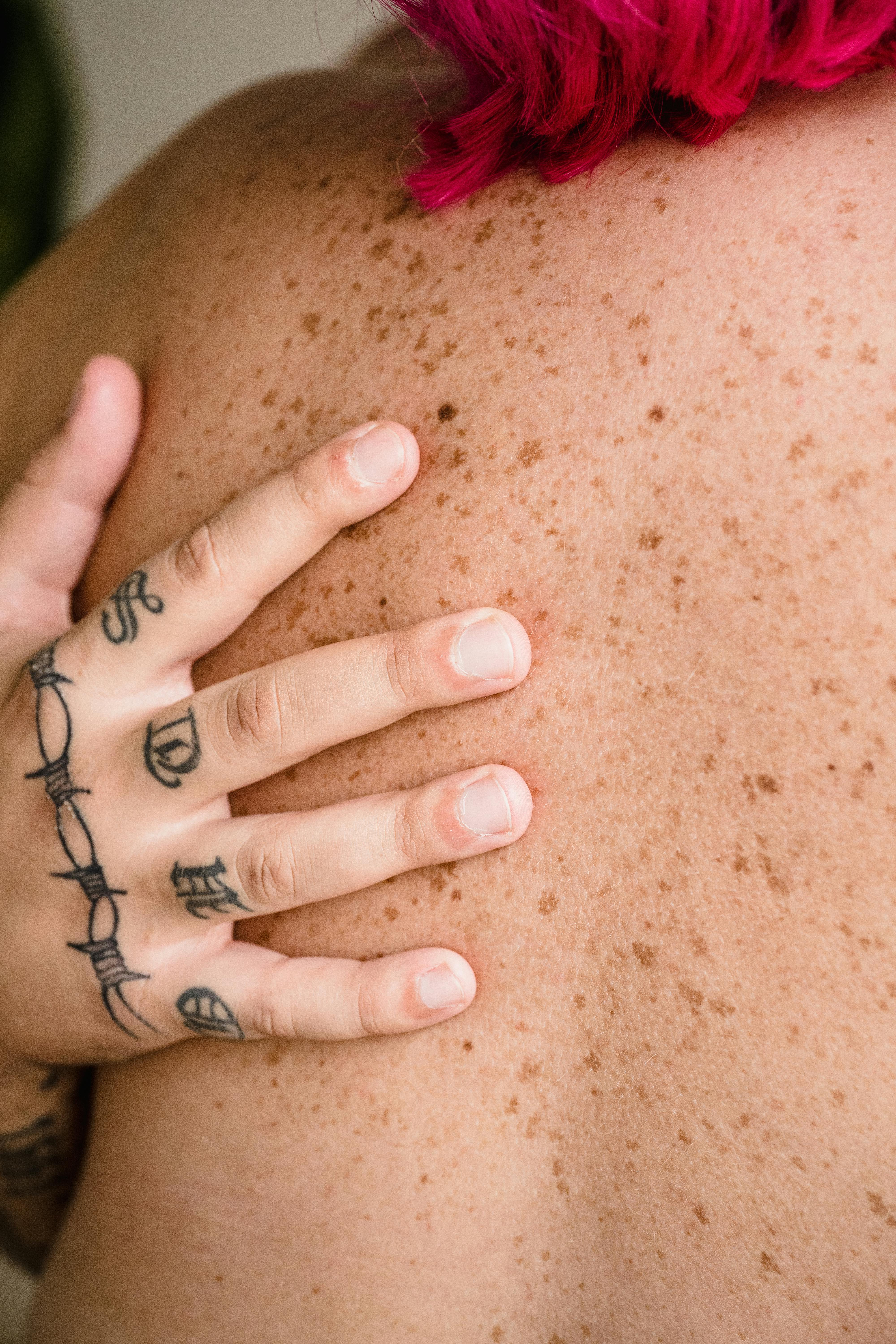 close up of tattooed hand of a man on womans naked back