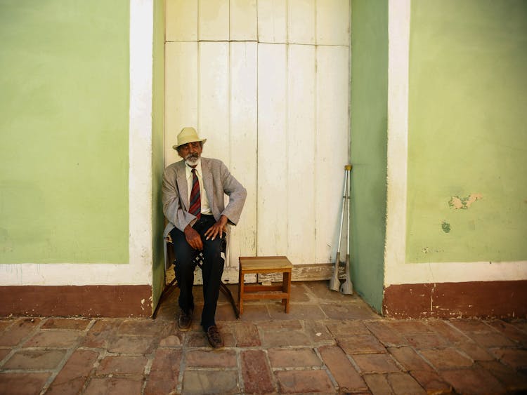 A Man In A Gray Suit Jacket Sitting On A Chair