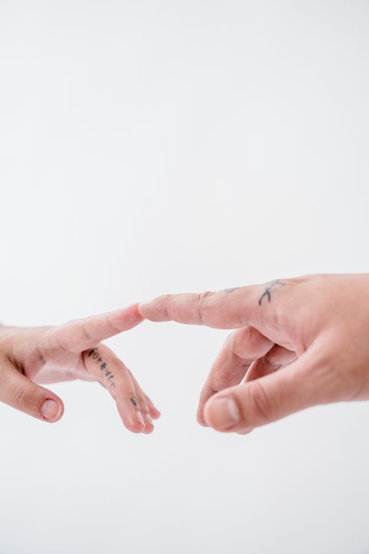 Close-up Of A Tattooed Couple Touching With Their Fingertips