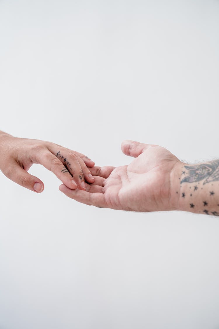 Close-up Of A Tattooed Couple Touching With Their Fingertips