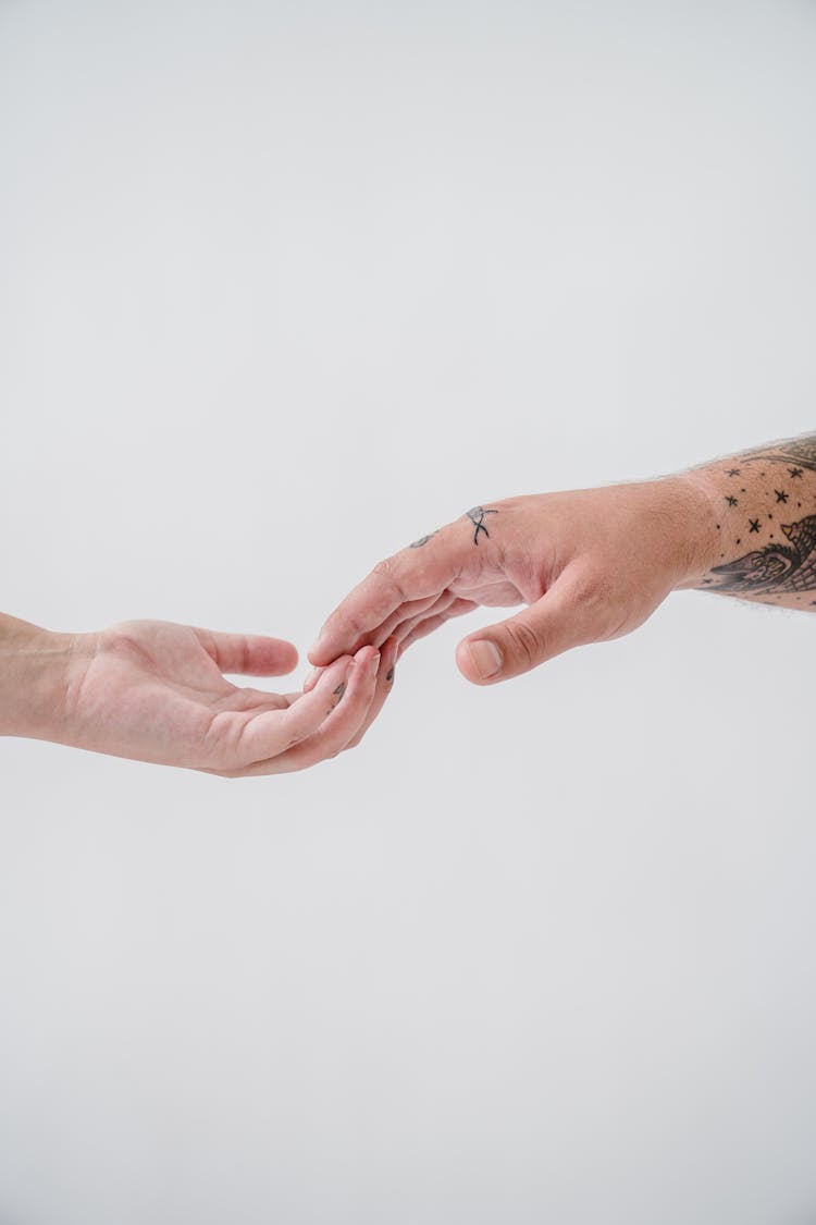 Close-up Of A Tattooed Couple Touching With Their Fingertips