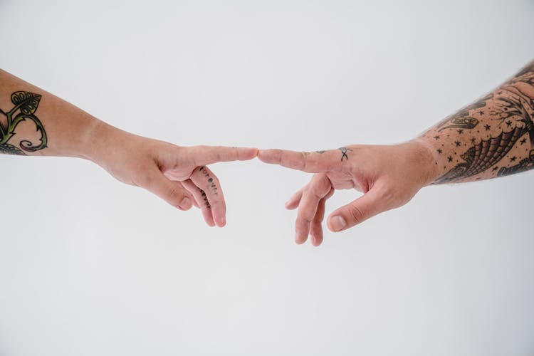 Close-up Of A Tattooed Couple Touching With Their Fingertips