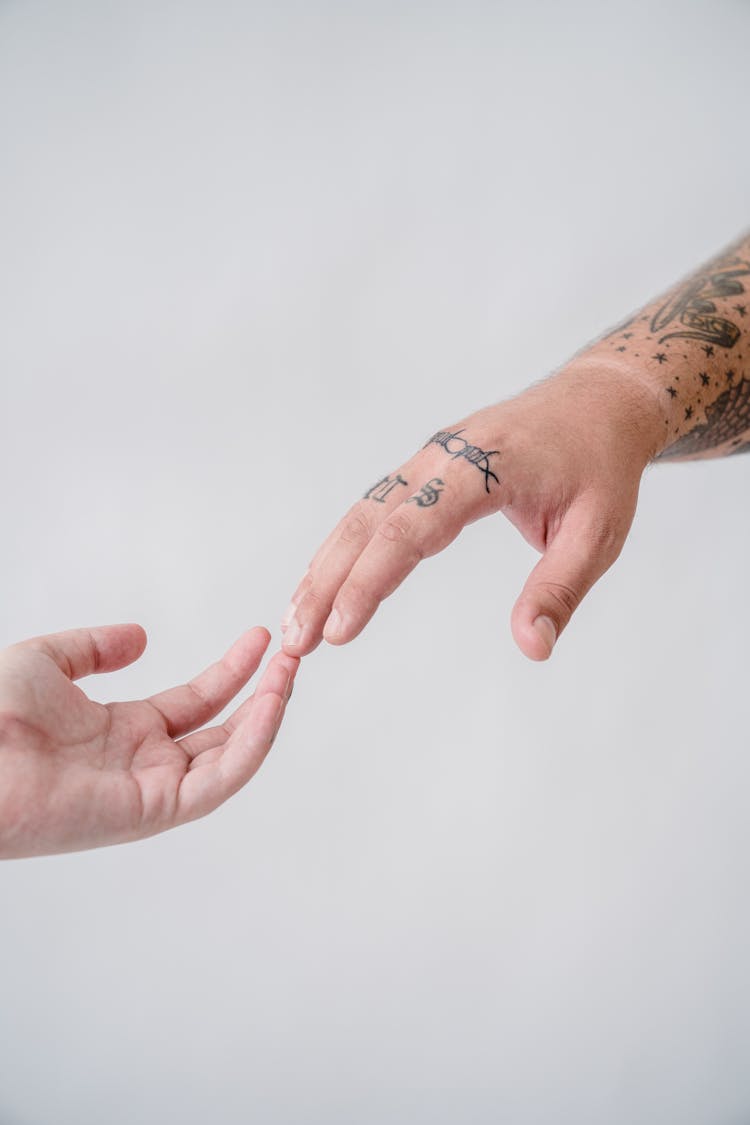 Close-up Of A Tattooed Couple Touching With Their Fingertips