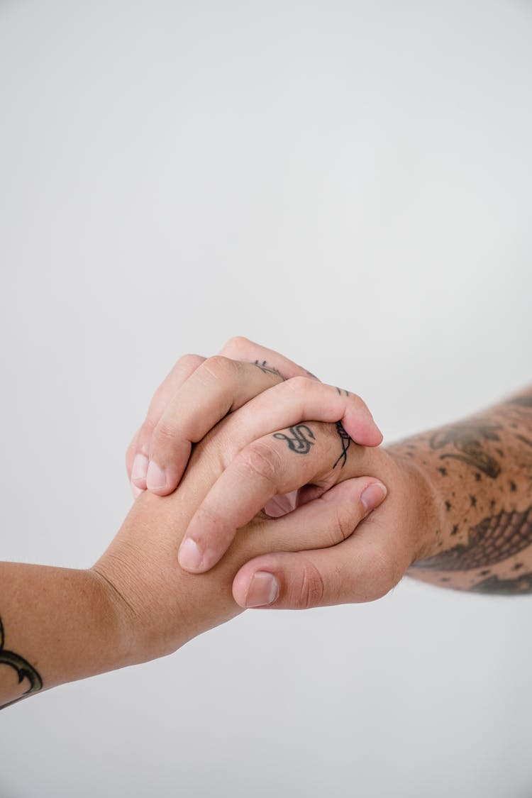 Close-up Of A Tattooed Couple Intertwined Hands 