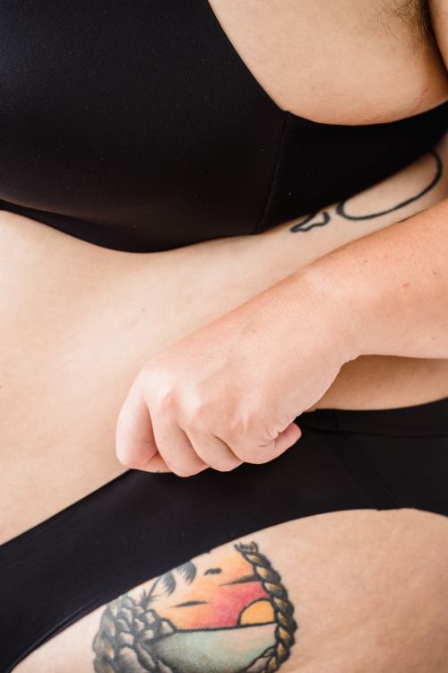 Free Artistic close-up photo showcasing a plus size woman's tattoos in black lingerie. Stock Photo