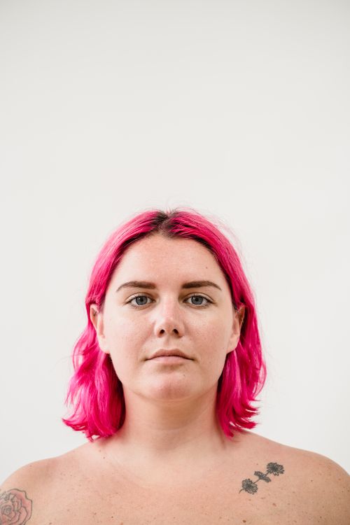 Free Close-up portrait of a woman with pink hair against a white background, providing ample copy space. Stock Photo