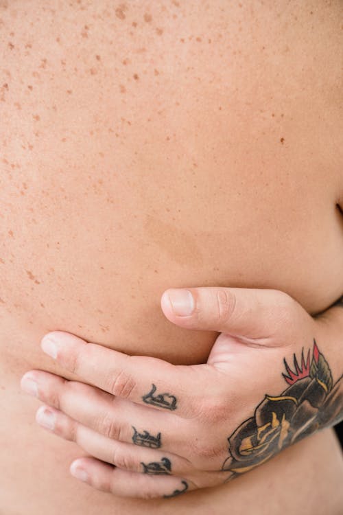 Close-up of a Tattooed Hand of a Man on Womans Bare Back 