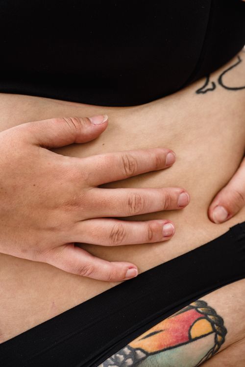 Free A close-up of a woman's hands touching her tattooed abdomen, expressing body art. Stock Photo