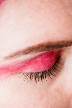 Detailed close-up of a woman's eyelid adorned with vibrant pink eyeshadow creating a fashion statement.