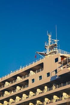 A luxury cruise ship with multiple balconies against a bright blue sky, showcasing modern maritime architecture.