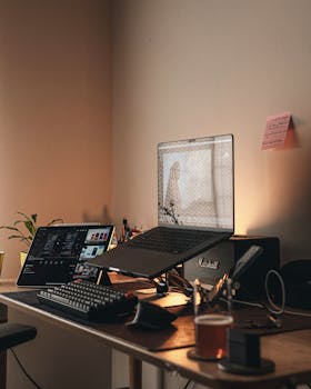 A warm, minimalist home office setup featuring a laptop, keyboard, and ambient lighting.