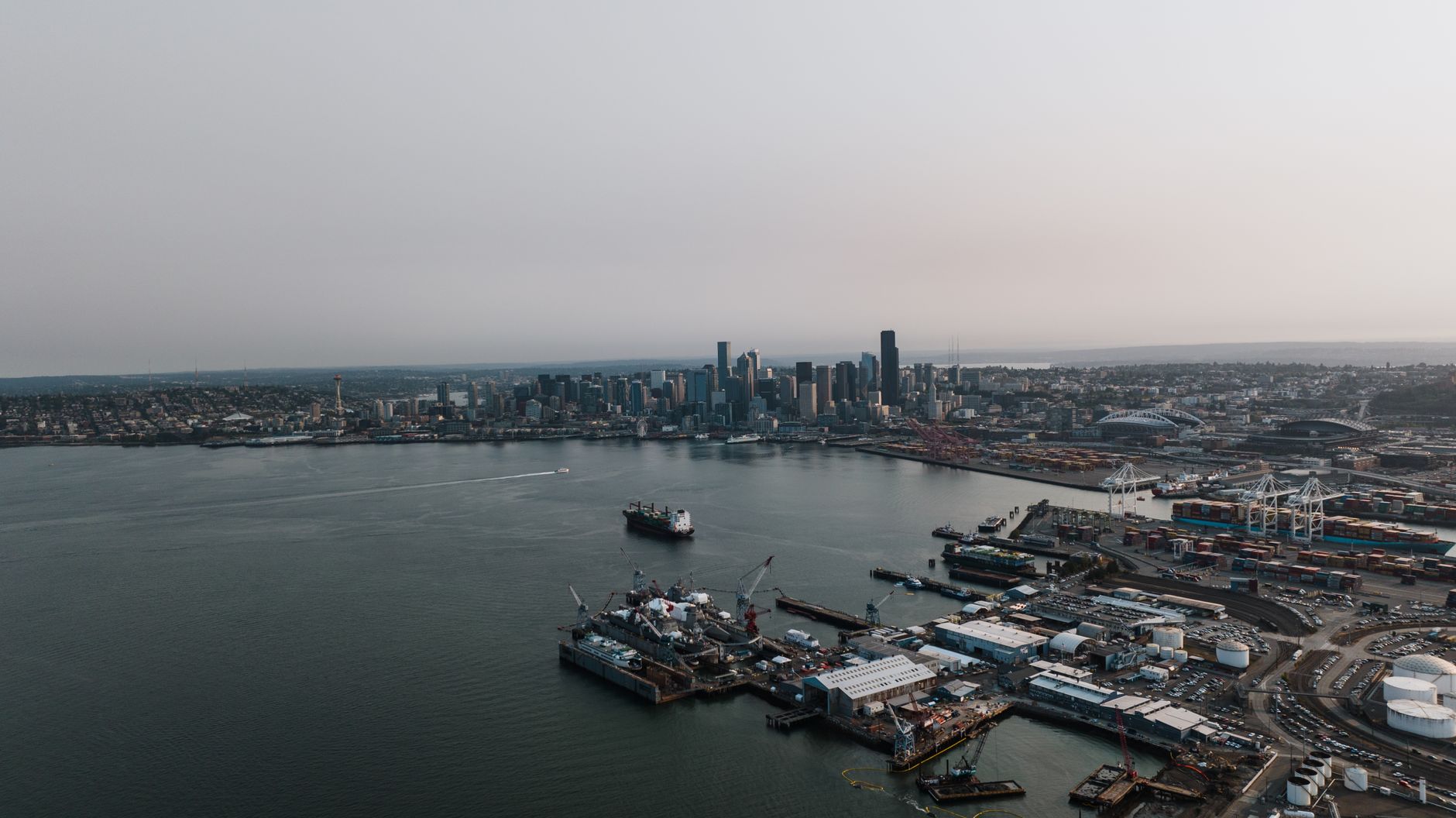 Aerial photography of Seattle's bustling harbor and skyline under a gloomy sky.