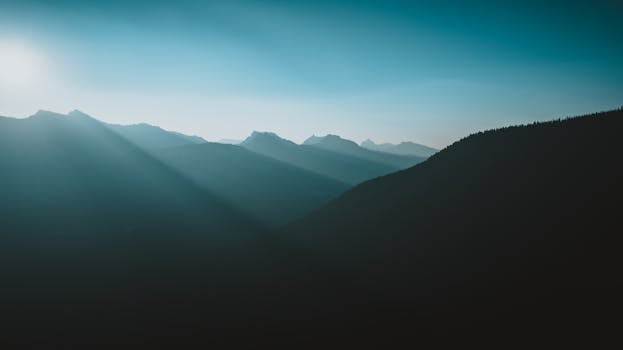 Capture of a serene mountain landscape at sunrise with sunrays illuminating the peaks in Washington.