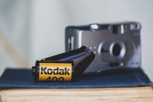 Gray Camera and Kodak Film on Brown Wooden Table