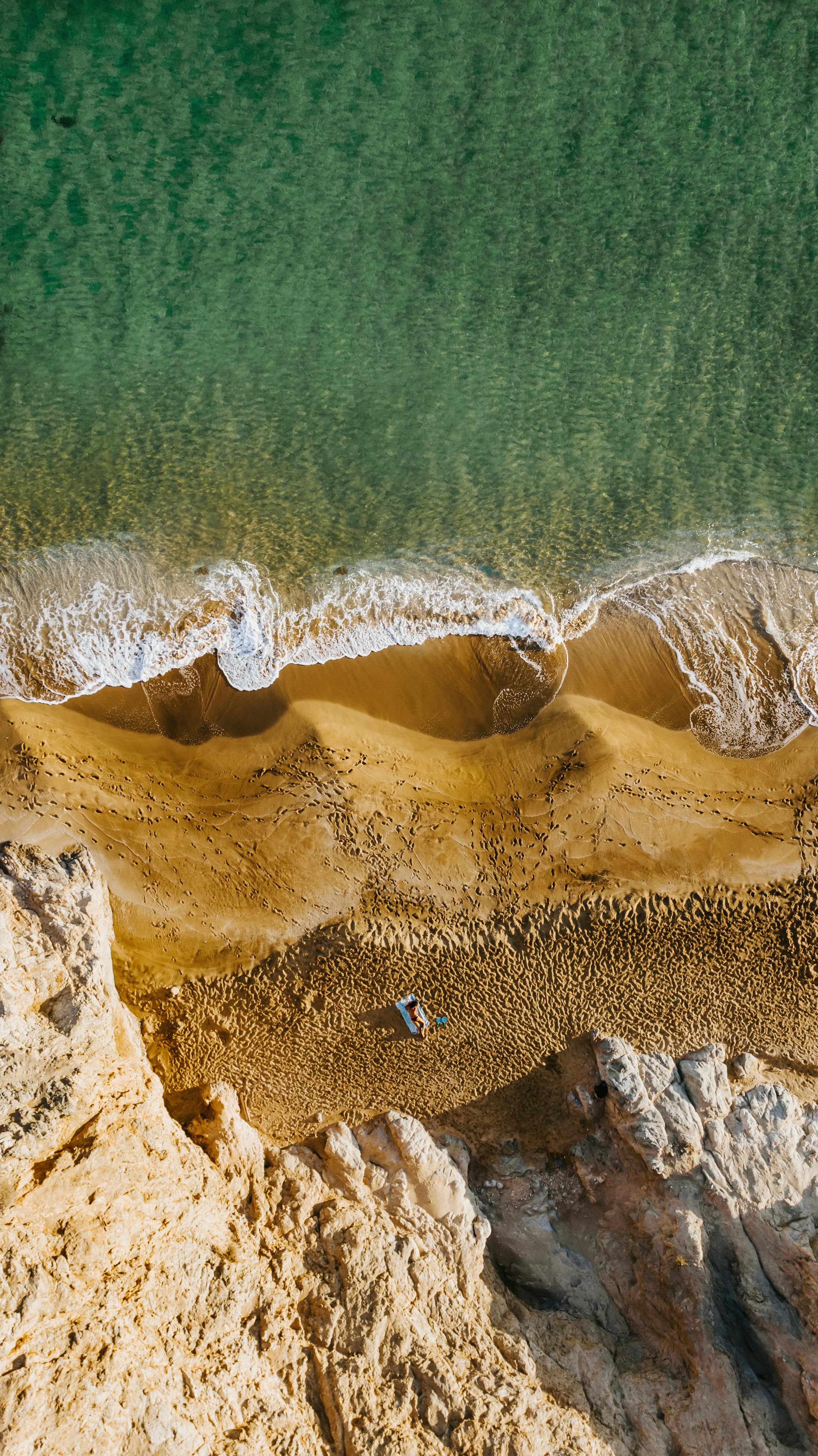 A breathtaking aerial view of a sandy beach meeting the turquoise ocean, perfect for travel inspiration.