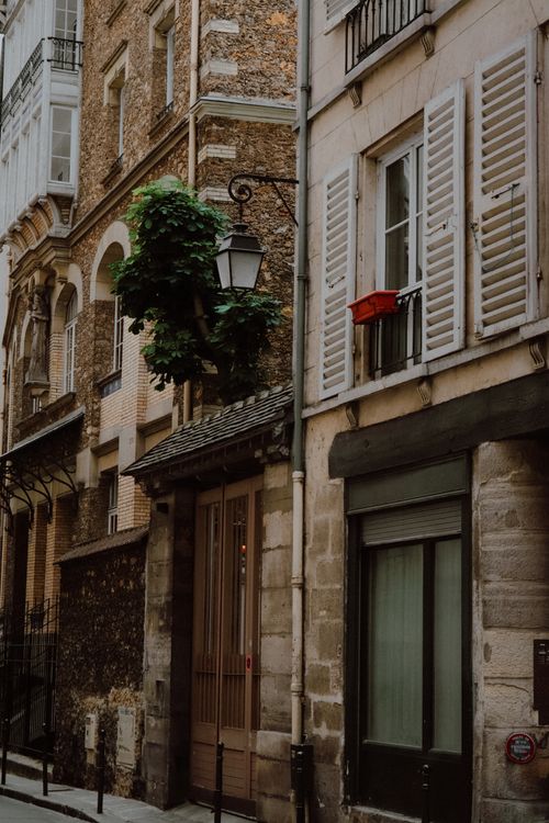 Free Classic Parisian street scene with traditional building facade, shutters, and hanging lamp, showcasing timeless architecture. Stock Photo