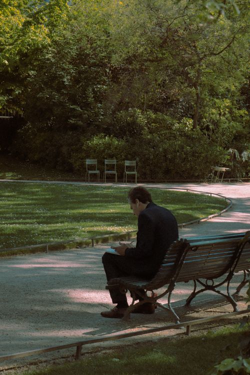 Free A man sits on a bench reading in a serene Paris park on a sunny day. Stock Photo