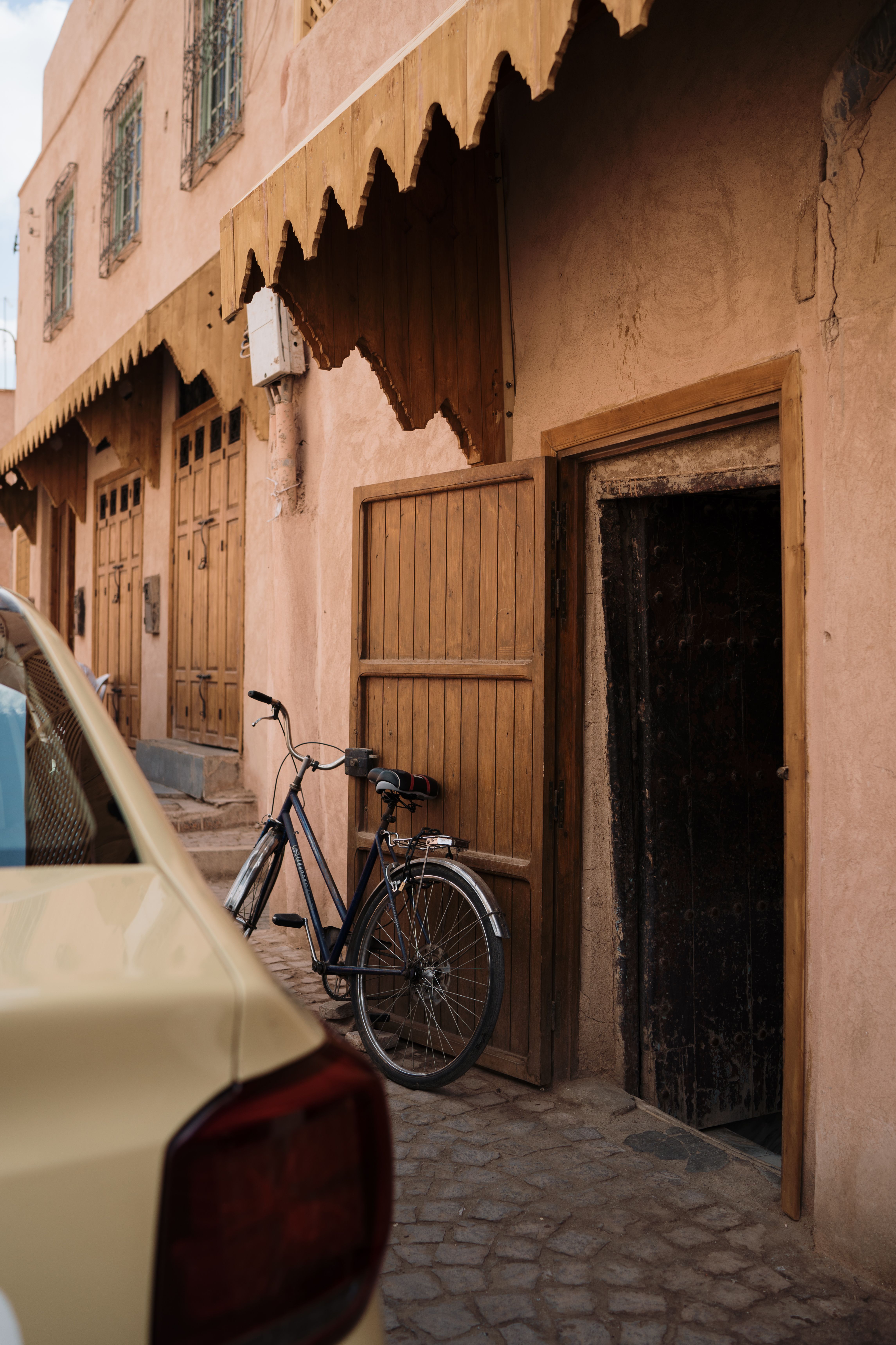 A vintage bicycle rests against a rustic wooden door on a quiet cobblestone street.