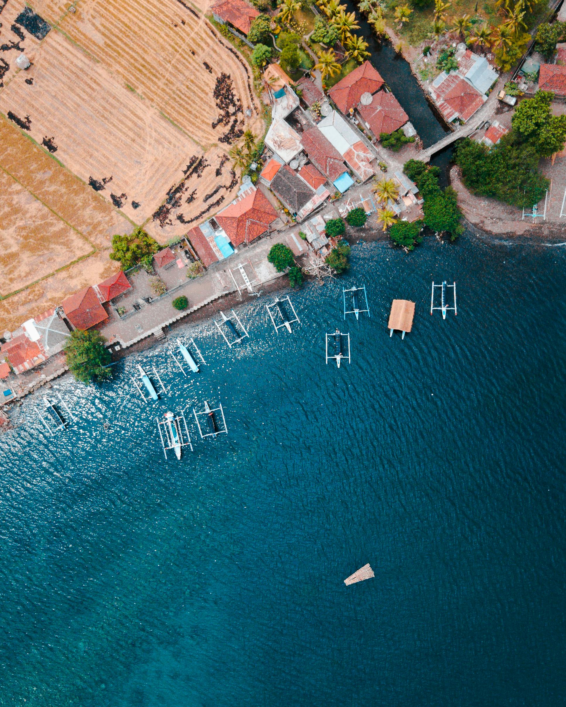 A breathtaking aerial view of Buleleng's coastline in Bali, featuring boats and vibrant blue sea.
