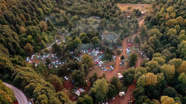 Drone shot capturing a vibrant campsite nestled within a dense forest setting.