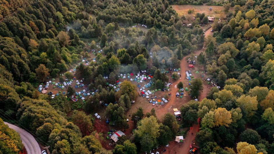 Drone shot capturing a vibrant campsite nestled within a dense forest setting.