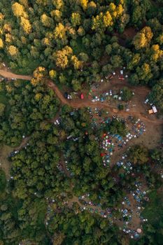 Stunning aerial drone shot capturing multiple tents in a vibrant forest campsite.