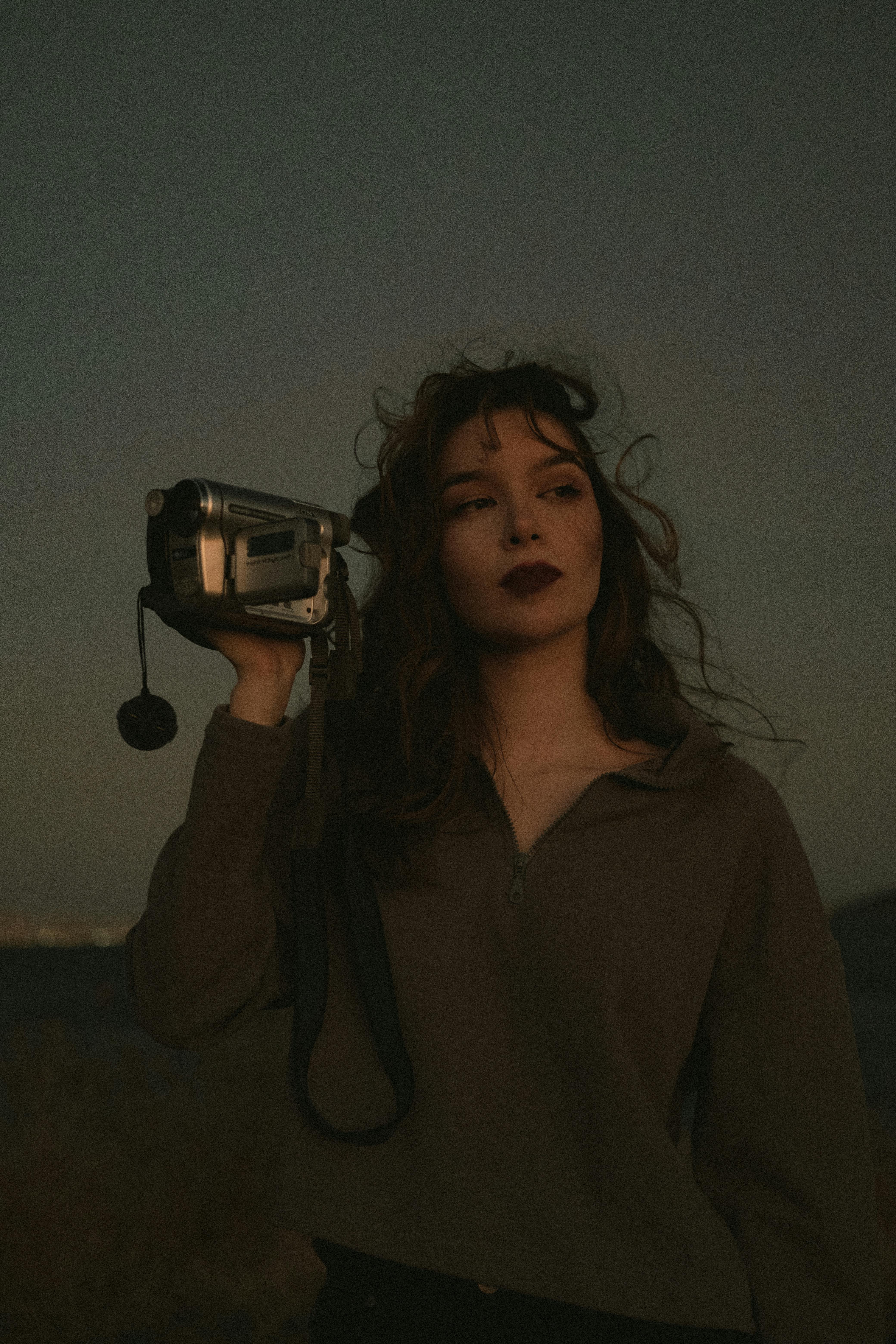 portrait of a woman in brown long sleeve shirt holding a video camera