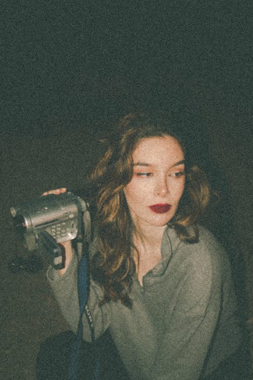 A Woman with Red Lips Holding an Old Video Camera