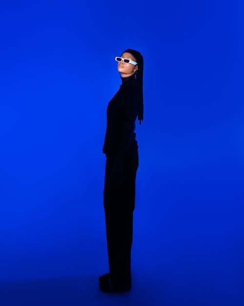 Woman in Black Clothes Standing on Blue Background