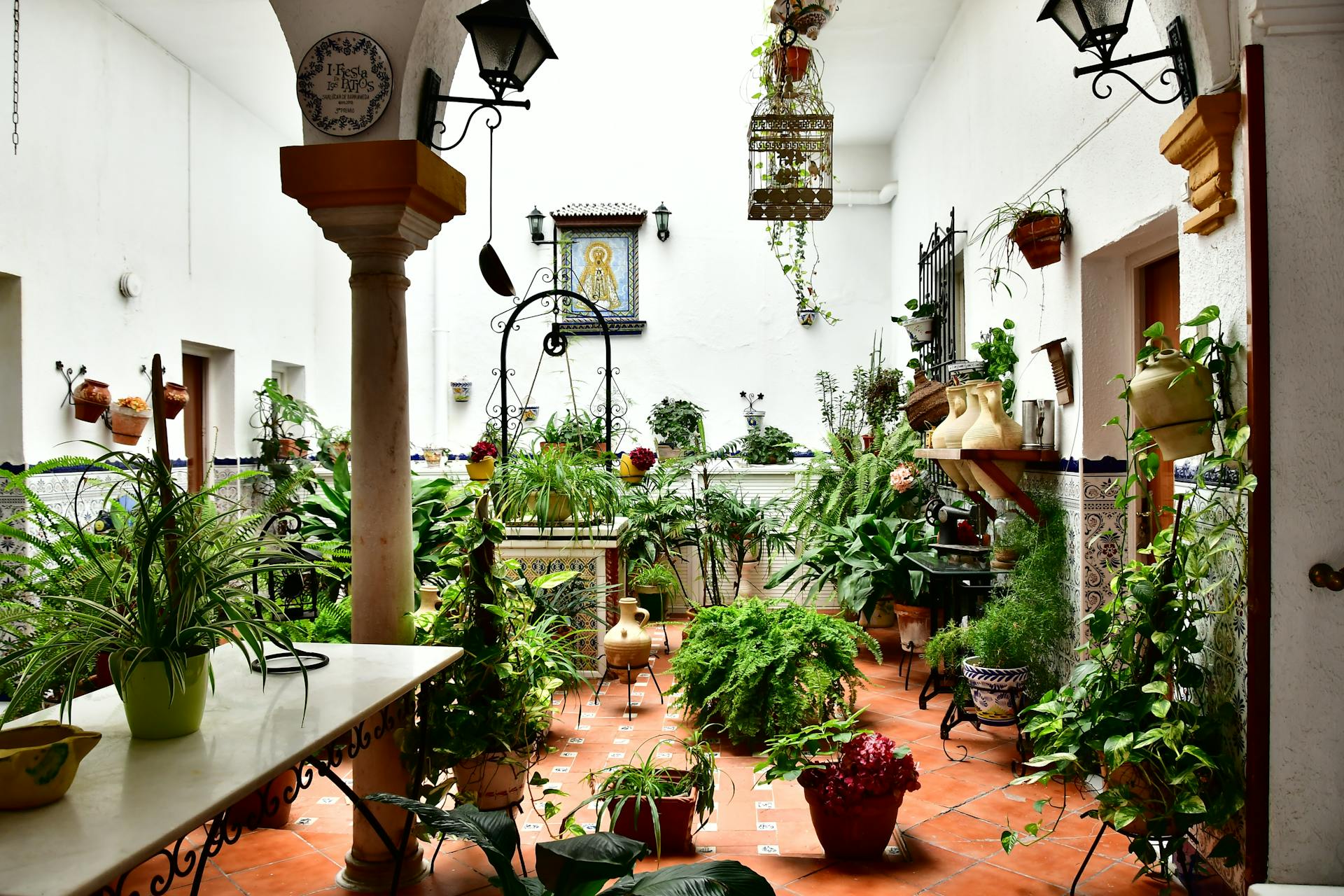 A vibrant Spanish courtyard filled with diverse plants and traditional decorations.