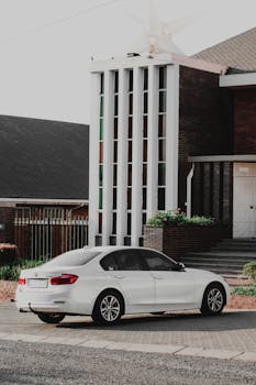 Elegant white BMW sedan parked outdoors next to a stylish modern building facade.
