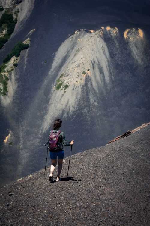 Free A woman hikes down a steep volcanic slope using trekking poles, capturing a sense of adventure. Stock Photo