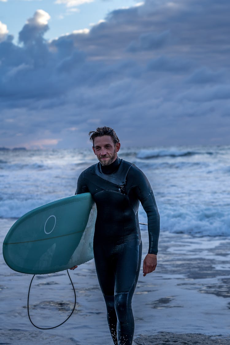 A Man Carrying A Surfboard