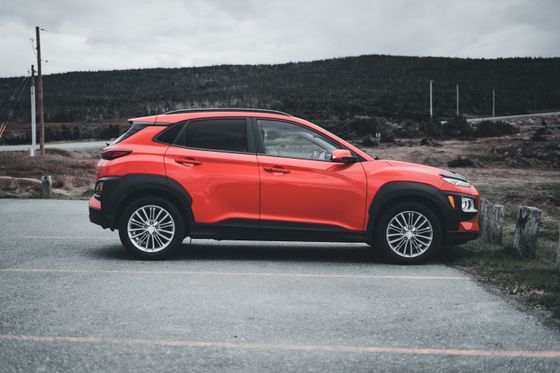 Red compact crossover in side profile with low hills behind. Photo by Erik Mclean on Pexels