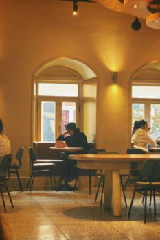 Warm toned coffee shop with seating areas and customers enjoying beverages.