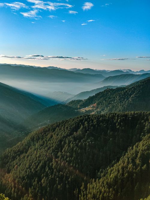 Free Breathtaking aerial view of Chail's lush green forests and majestic mountains under a clear blue sky. Stock Photo