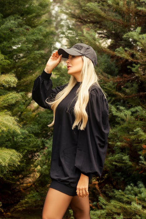 Blonde in Baseball Hat near Spruce Trees