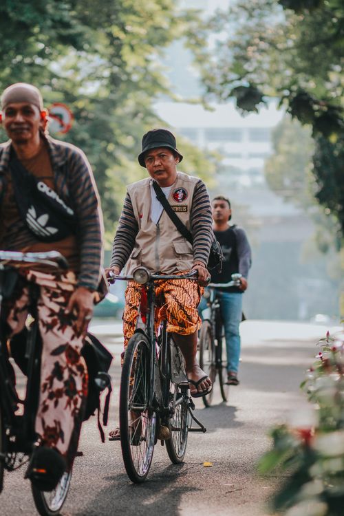 Free Group of men cycling through city streets, showcasing urban lifestyle and eco-friendly commuting. Stock Photo