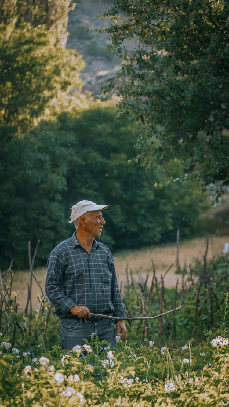 Man Standing In A Field Holding A Stick