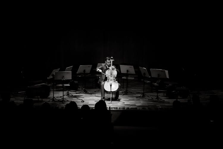 Black And White Photo Of Cellist Playing Alone On Stage