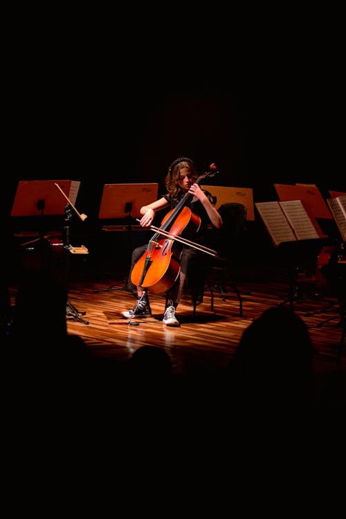 Woman Sitting on Stage and Playing Double Bass
