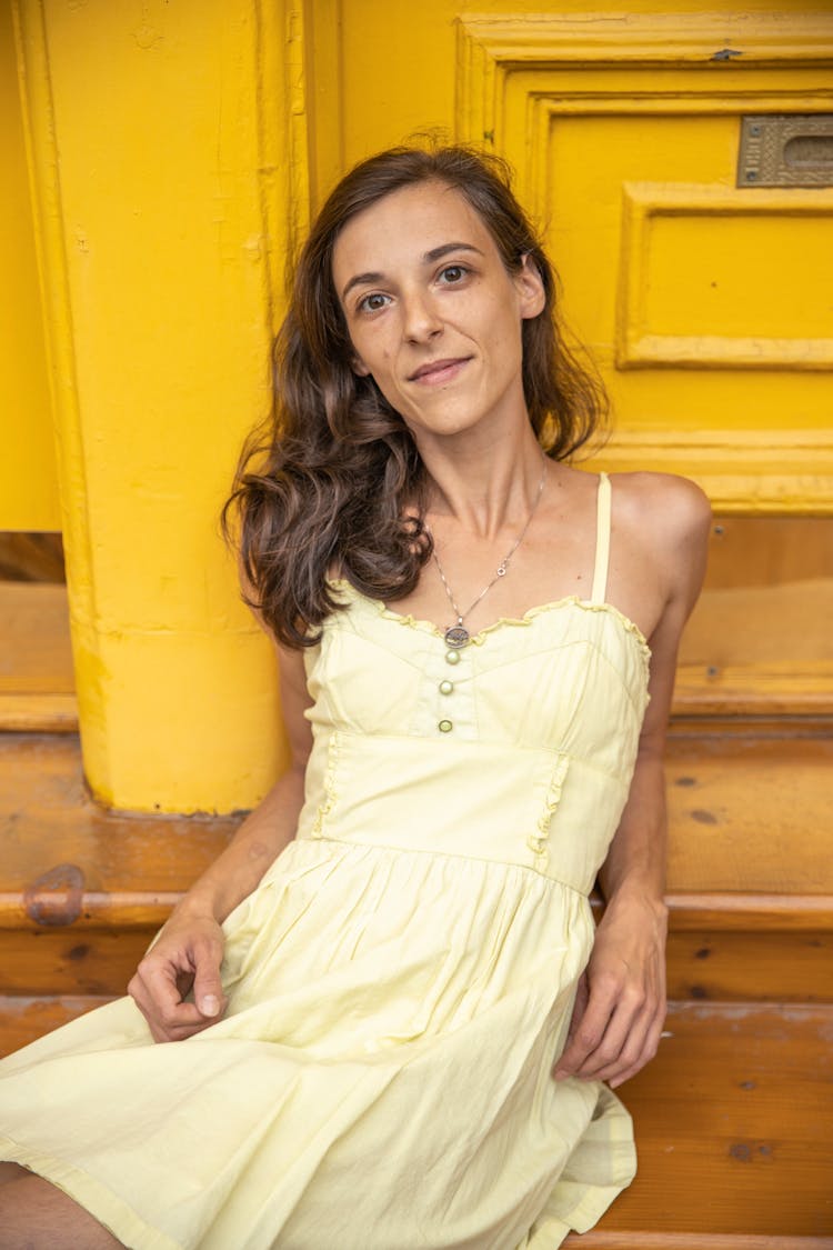 A Woman In Yellow Dress Sitting On Steps