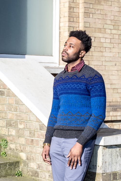 A Man in Blue Sweater Leaning on Concrete Railing