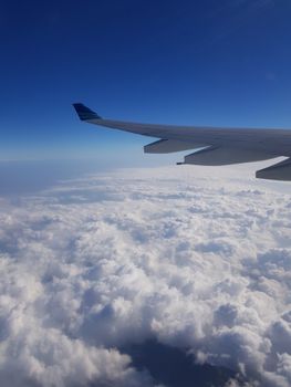 在晴朗的蓝天下，从蓬松的云层上看到飞机机翼，非常适合旅行和航空主题