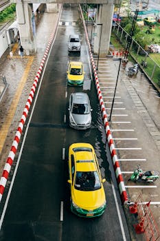 Vertical aerial shot of cars on a wet road lined with red and white barriers on a rainy day.