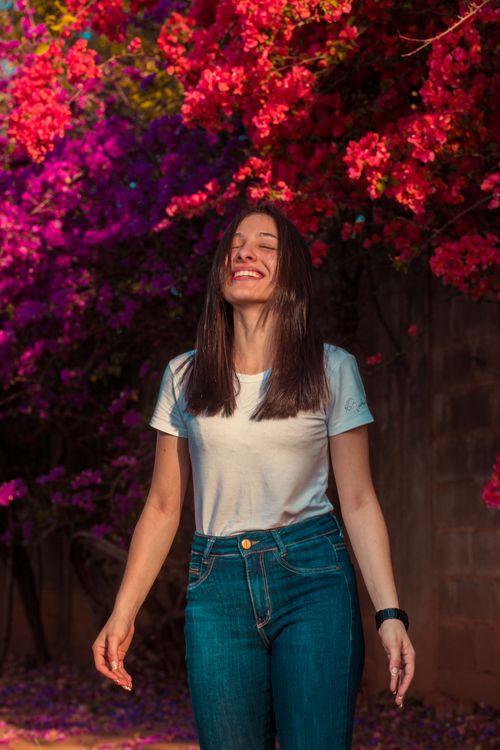 Free Joyful woman enjoying a sunny day outdoors, surrounded by beautiful bougainvillea blooms. Stock Photo